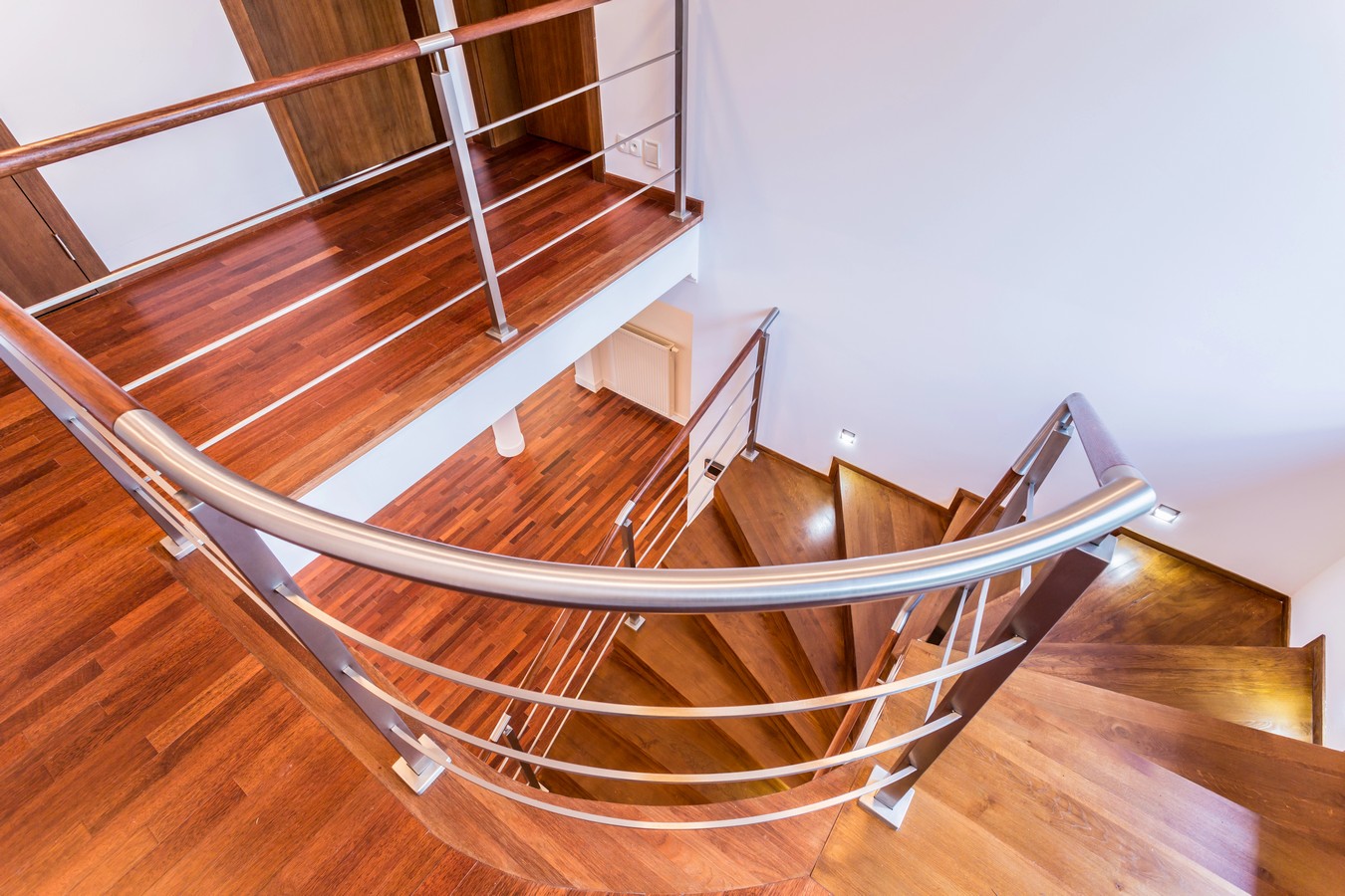 Curved hardwood staircase with steel balustrade showcasing railing design options
