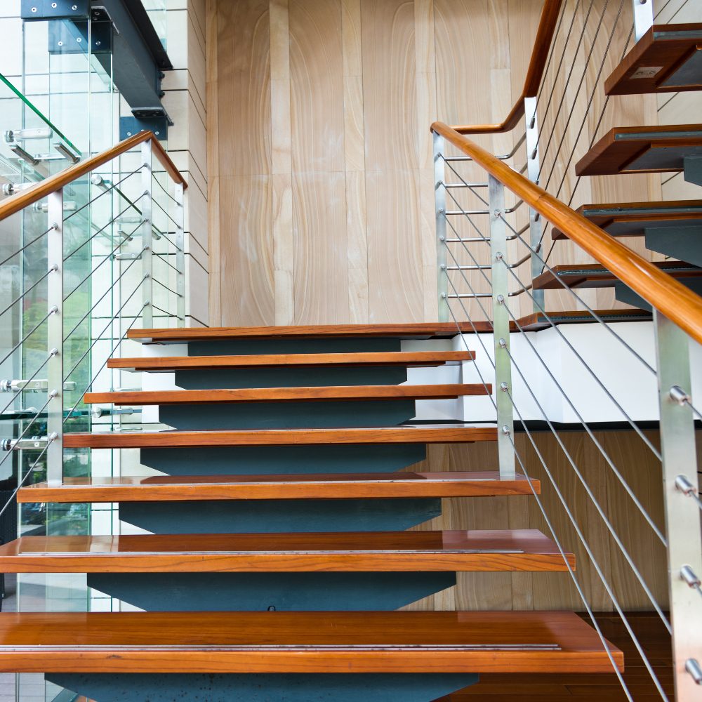 Open-tread timber staircase with glass and wire balustrade in a Queensland home