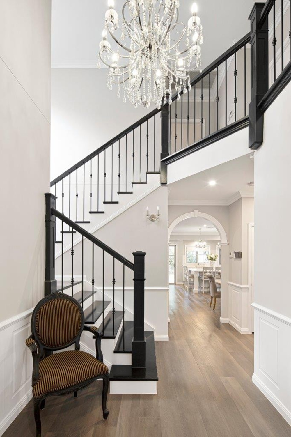 U-shaped staircase with black balustrade and chandelier